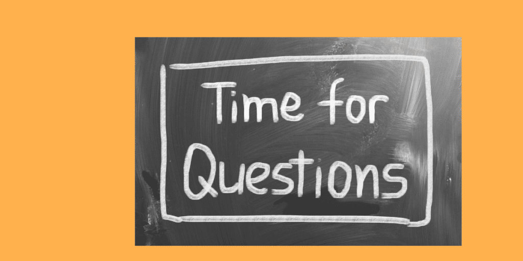 "A person is using chalk to write the phrase 'Time for Questions' in white block letters on a clean, black chalkboard. The text is framed by a hand-drawn white rectangle."